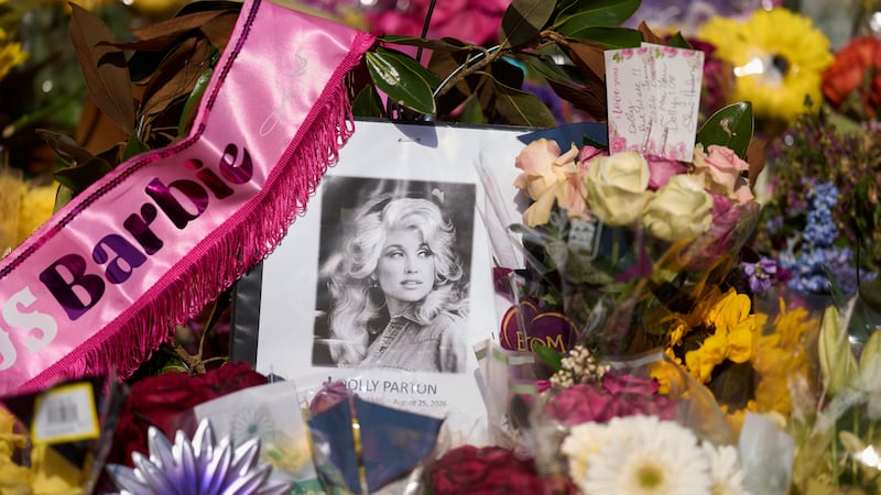 A portrait of the late Dolly Parton surrounded by flowers and cards in a memorial sits outside...