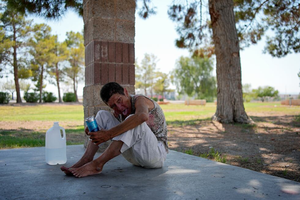 Deb Billet, 66, rests on the ground while drinking cold water given to her by Henderson Public...