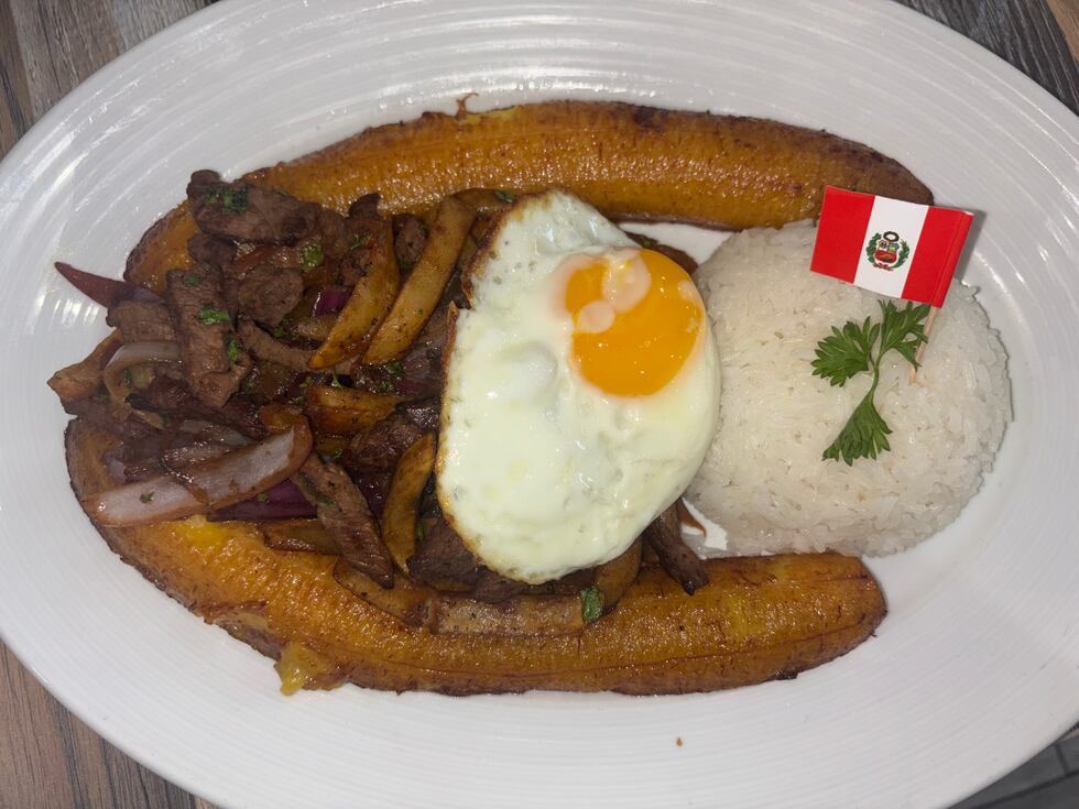 Lomo saltado steak made with peppers, onions and served with a fried egg, rice and fried...