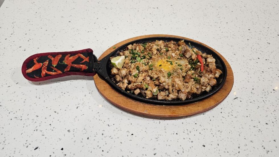 The sizzling sisig is made with pork belly, onions, ginger, a tangy dressing and topped with a...