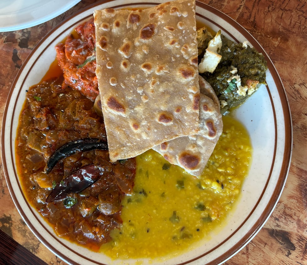 A buffet plate consisting of Butter Chicken, Palak Paneer, Bhindi Masala, Yellow Dal, and...