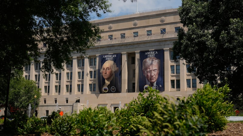 Banners of former President George Washington and President Donald Trump hang above an...