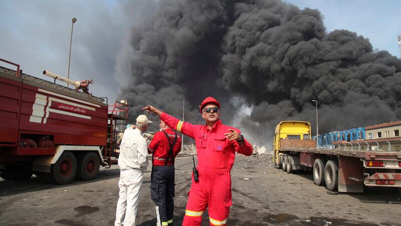In this photo provided by Islamic Republic News Agency (IRNA) firefighters work as black smoke...