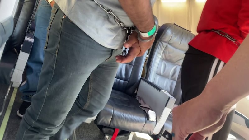 This photo from a former flight attendant shows a row of passengers with shackles on their...