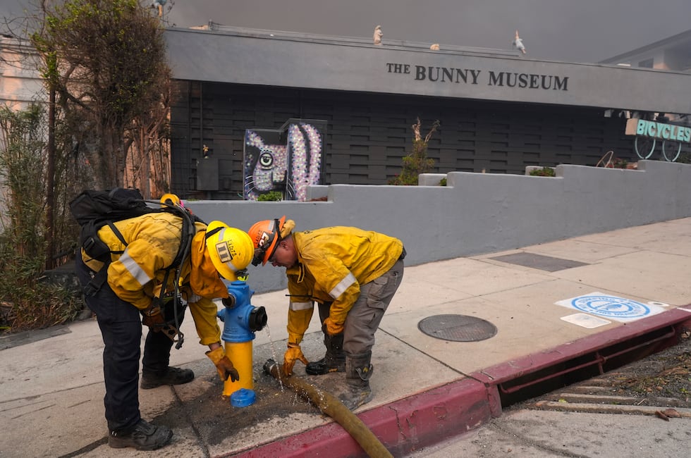 Firefighters work a hydrant in front of the burning Bunny Museum, Wednesday, Jan. 8, 2025, in...