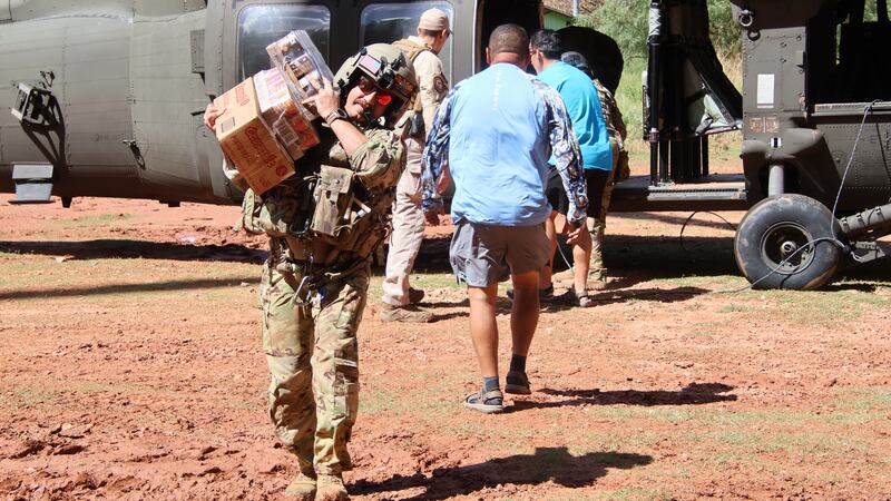 A U.S. Army Soldier of the Arizona National Guard (AZNG) unloads food supply from a UH-60...